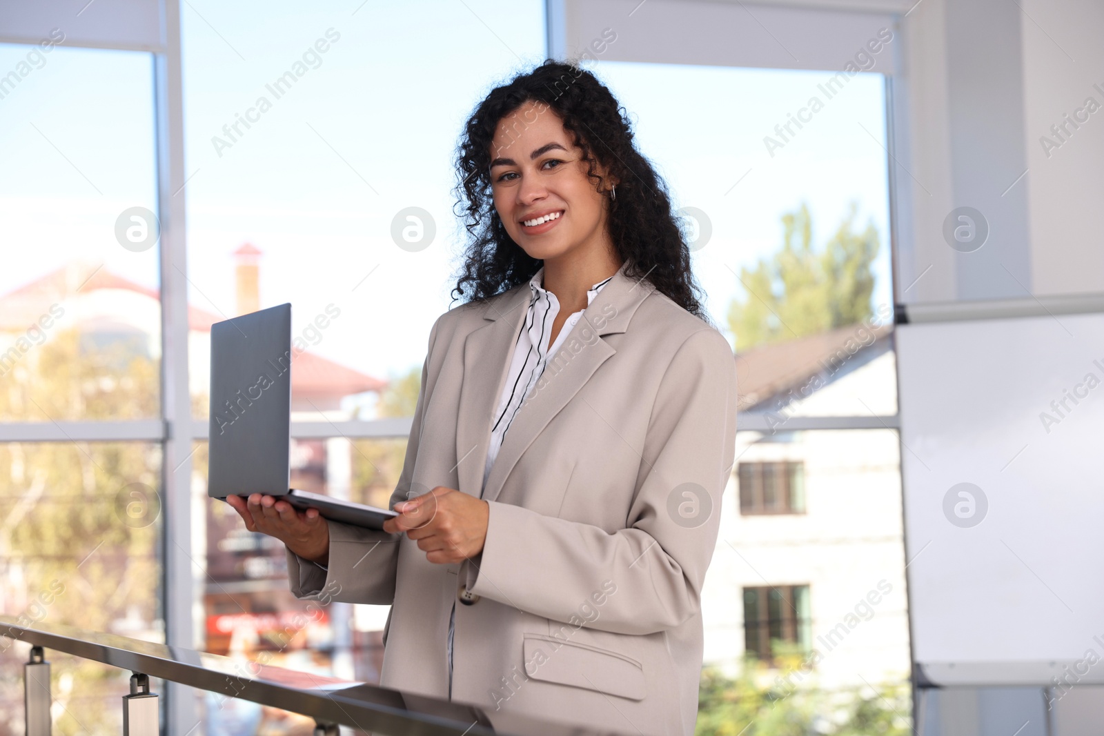 Photo of Portrait of young woman with laptop wearing stylish suit indoors