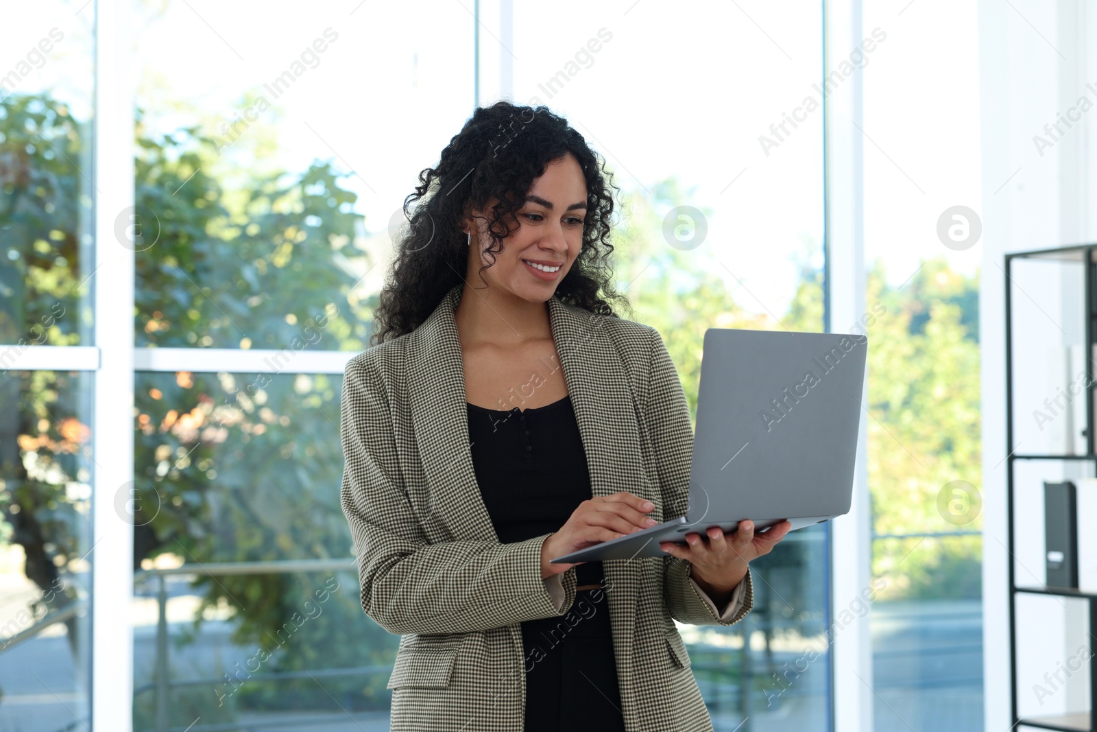 Photo of Portrait of young woman with laptop wearing stylish suit indoors