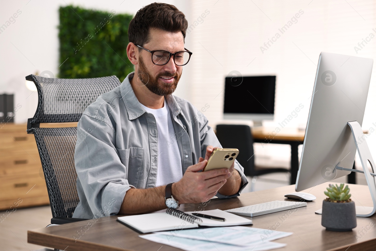 Photo of Man with smartphone working at table in office