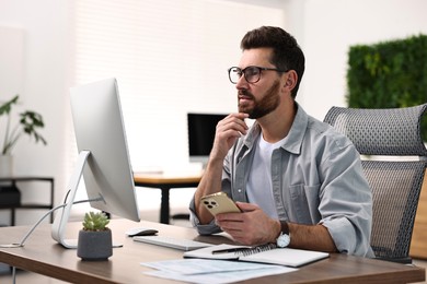 Photo of Man with smartphone working at table in office