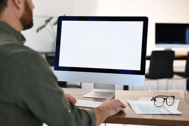 Photo of Man working on computer at table in office, closeup