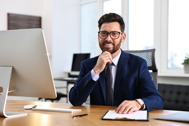 Photo of Man with glasses working at table in office