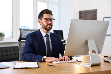 Photo of Man working on computer at table in office