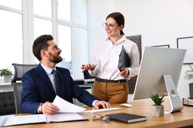 Photo of Colleagues working together at desk in office