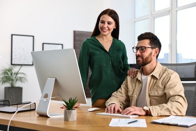 Photo of Colleagues working with computer at desk in office