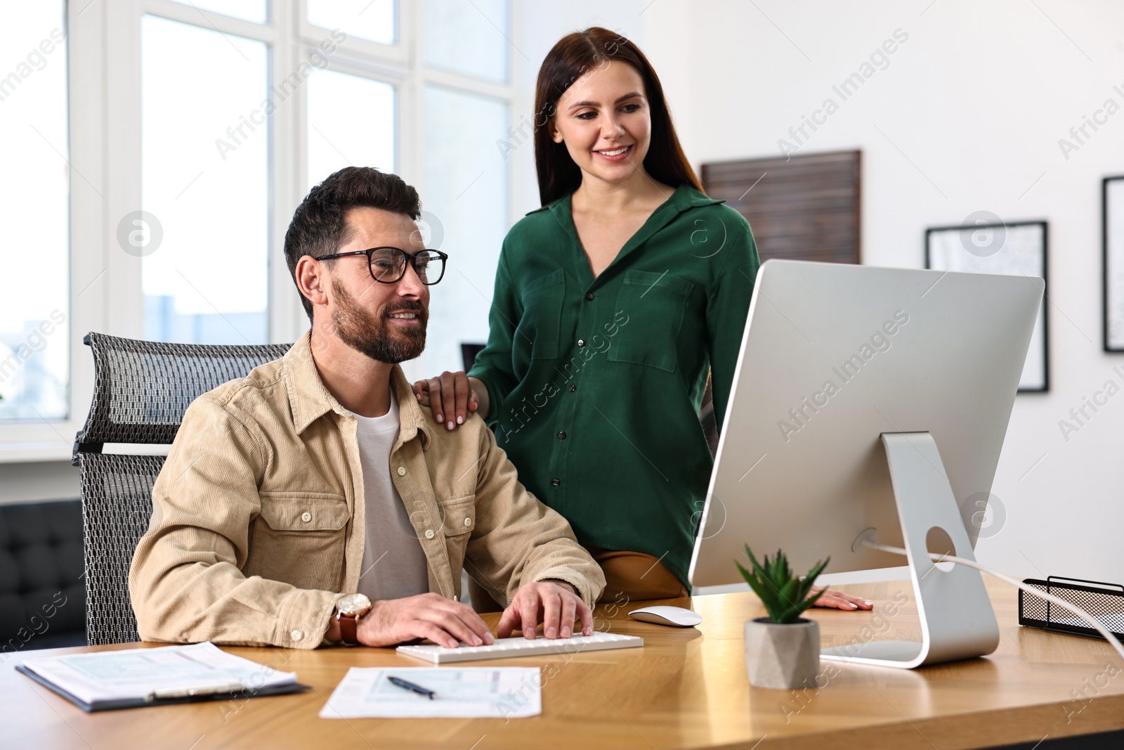 Photo of Colleagues working with computer at desk in office