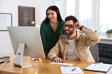 Photo of Colleagues working with computer at desk in office