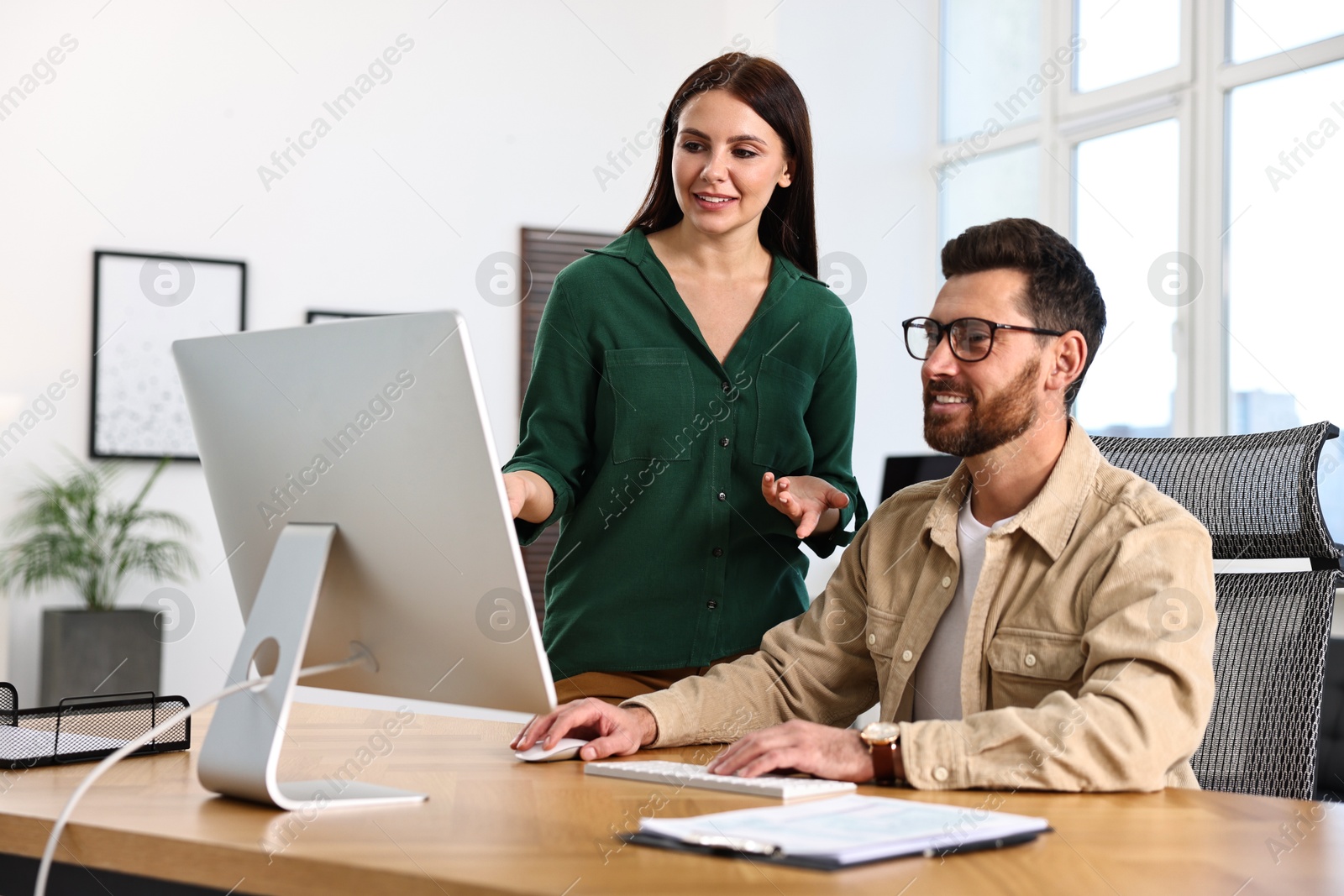 Photo of Colleagues working with computer at desk in office