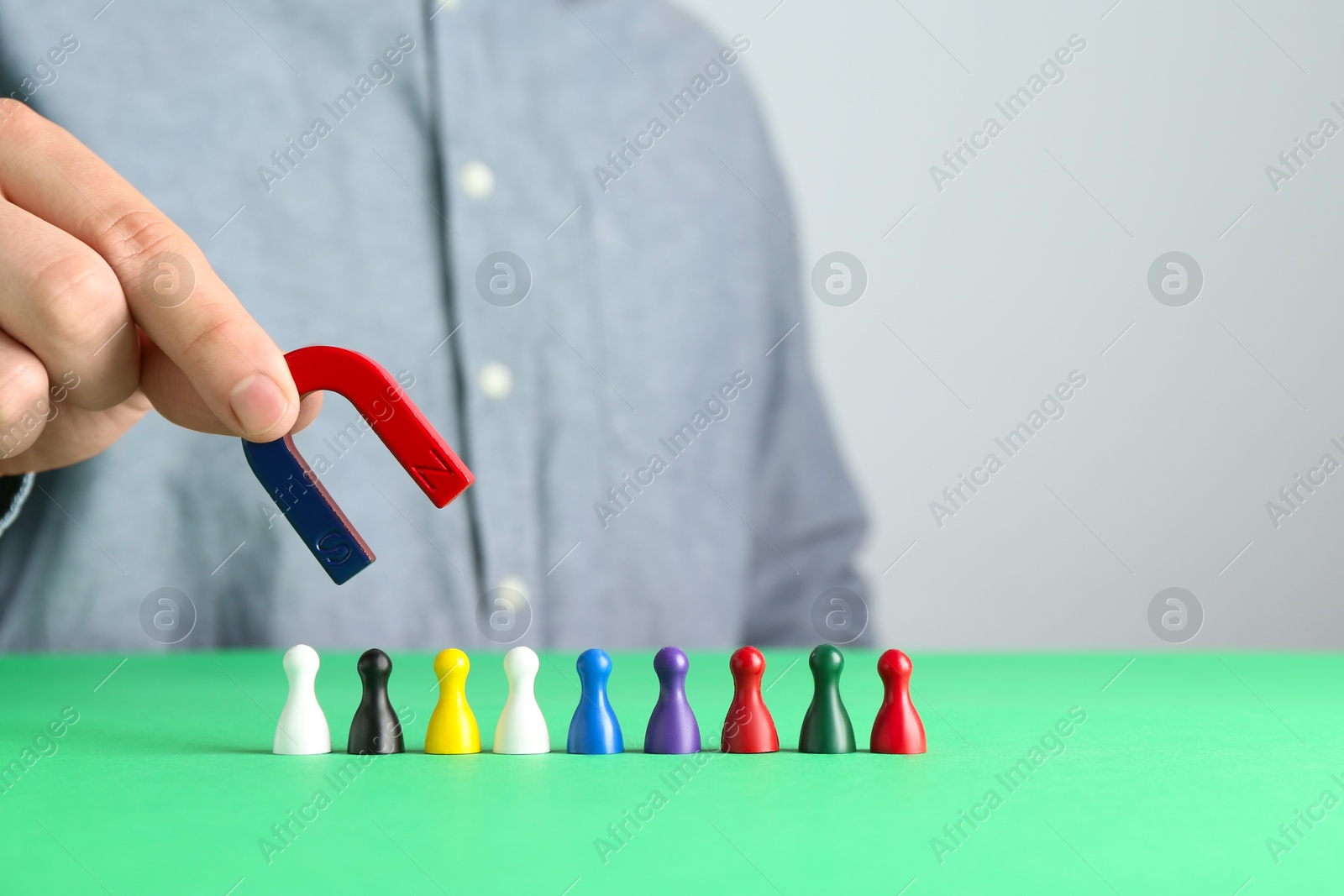 Photo of Man with magnet attracting game pieces at green table, closeup. Space for text