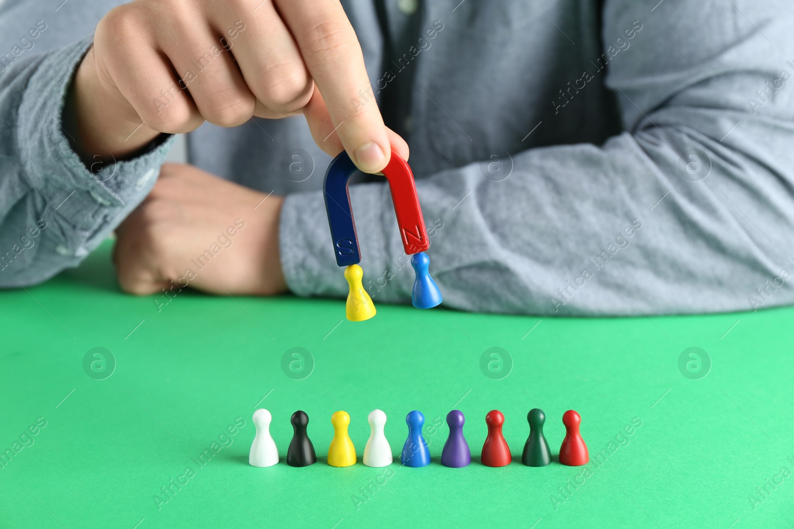 Photo of Man with magnet attracting game pieces at green table, closeup