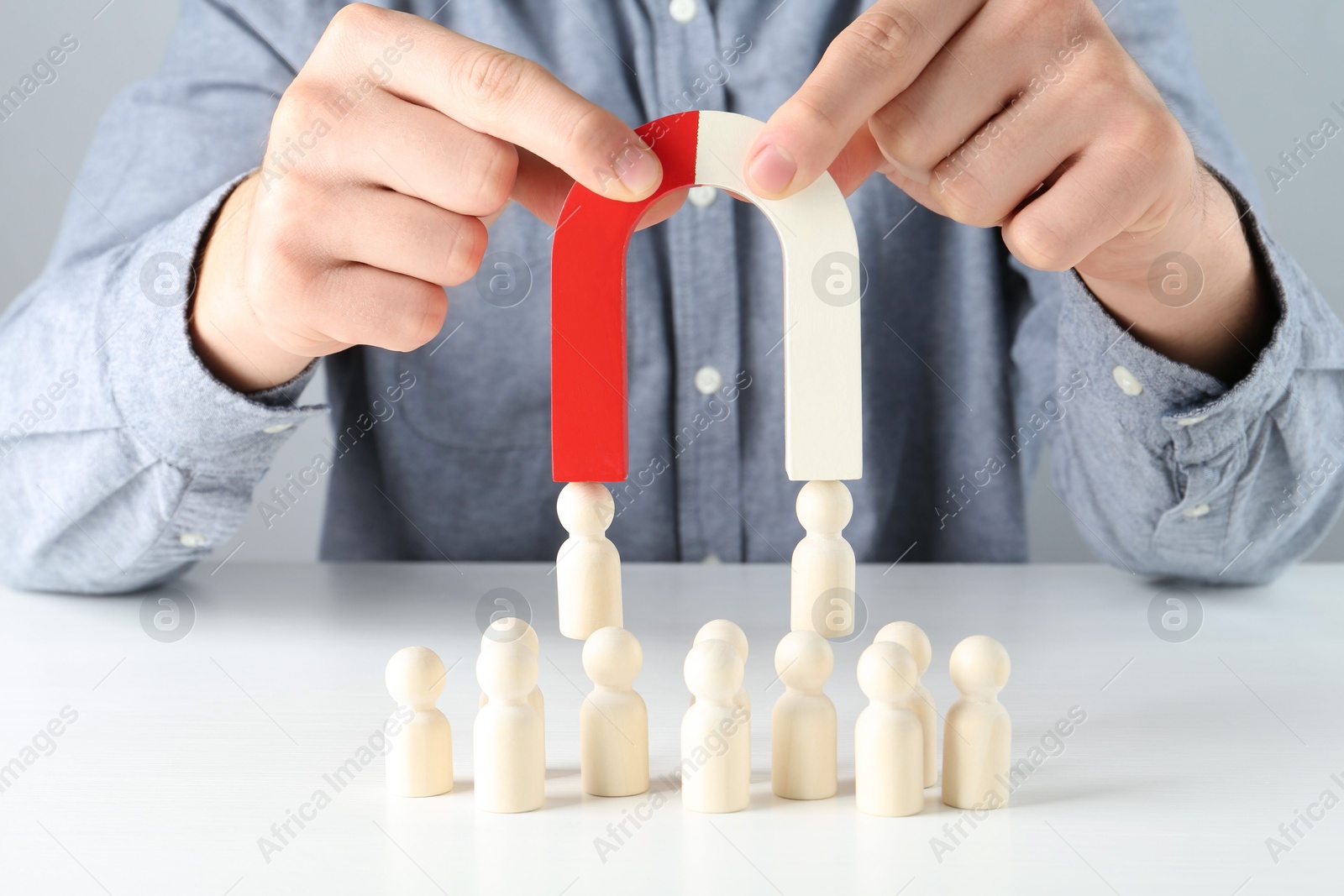 Photo of Man with magnet attracting game pieces at white table, closeup