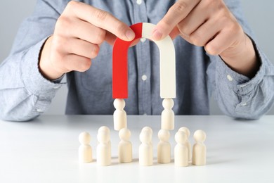 Photo of Man with magnet attracting game pieces at white table, closeup