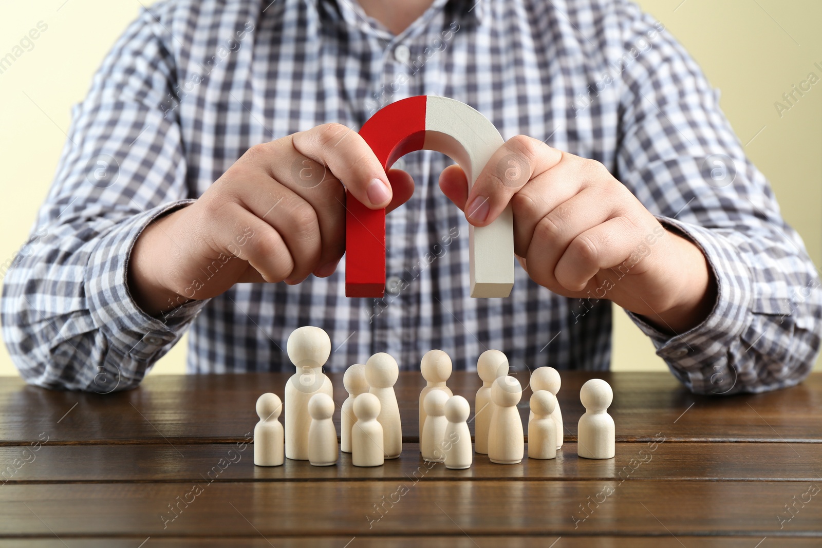 Photo of Man with magnet attracting game pieces at wooden table, closeup