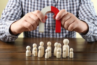 Photo of Man with magnet attracting game pieces at wooden table, closeup