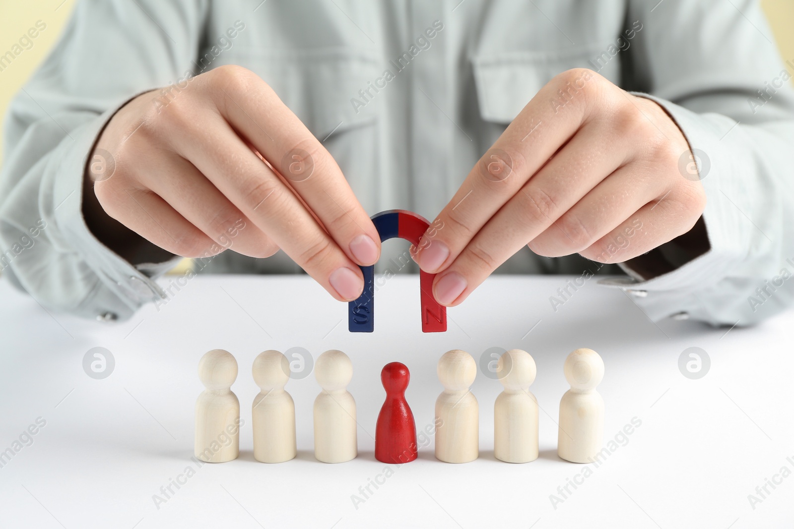 Photo of Woman with magnet attracting game pieces at white table, closeup