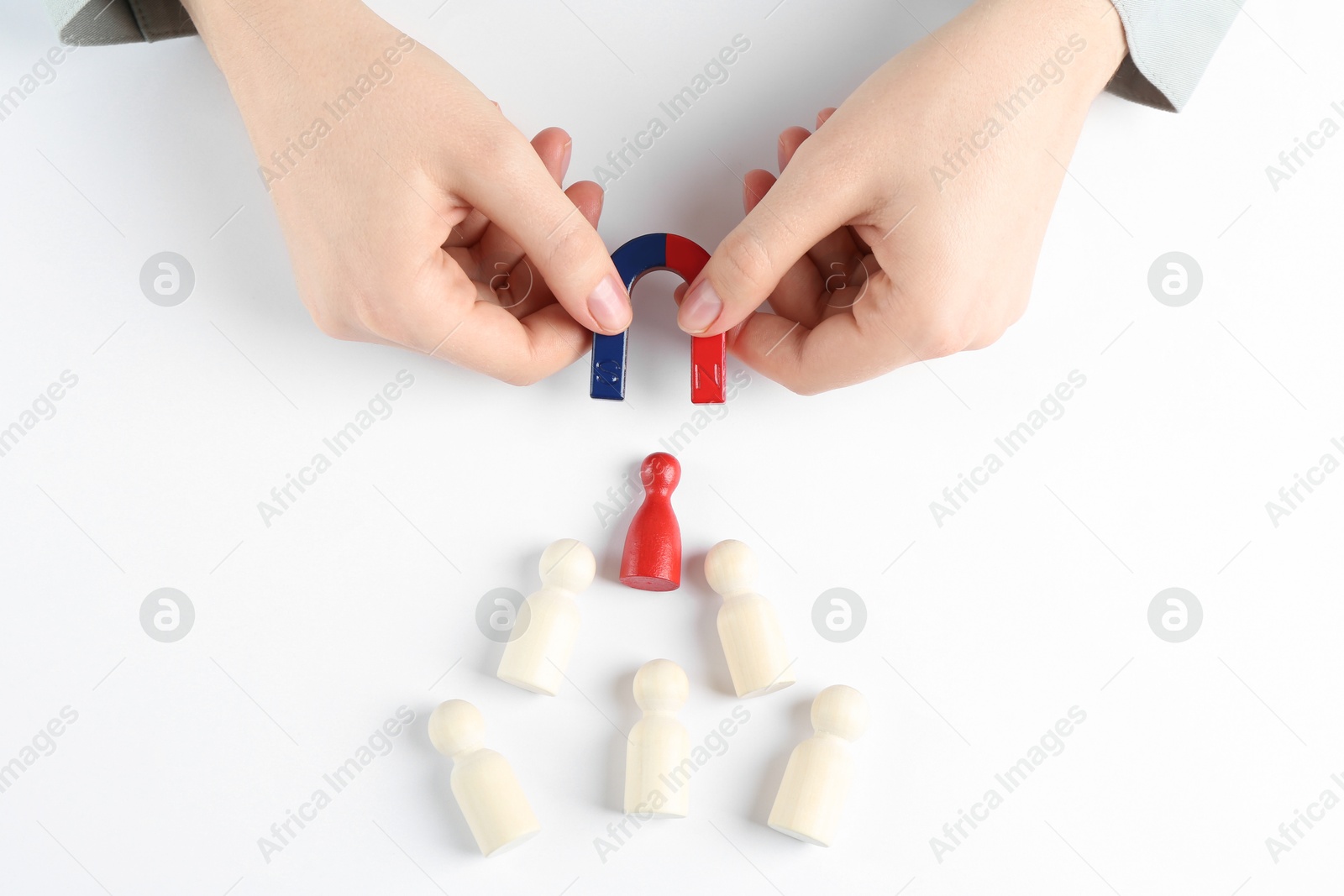 Photo of Woman with magnet attracting game pieces at white table, above view