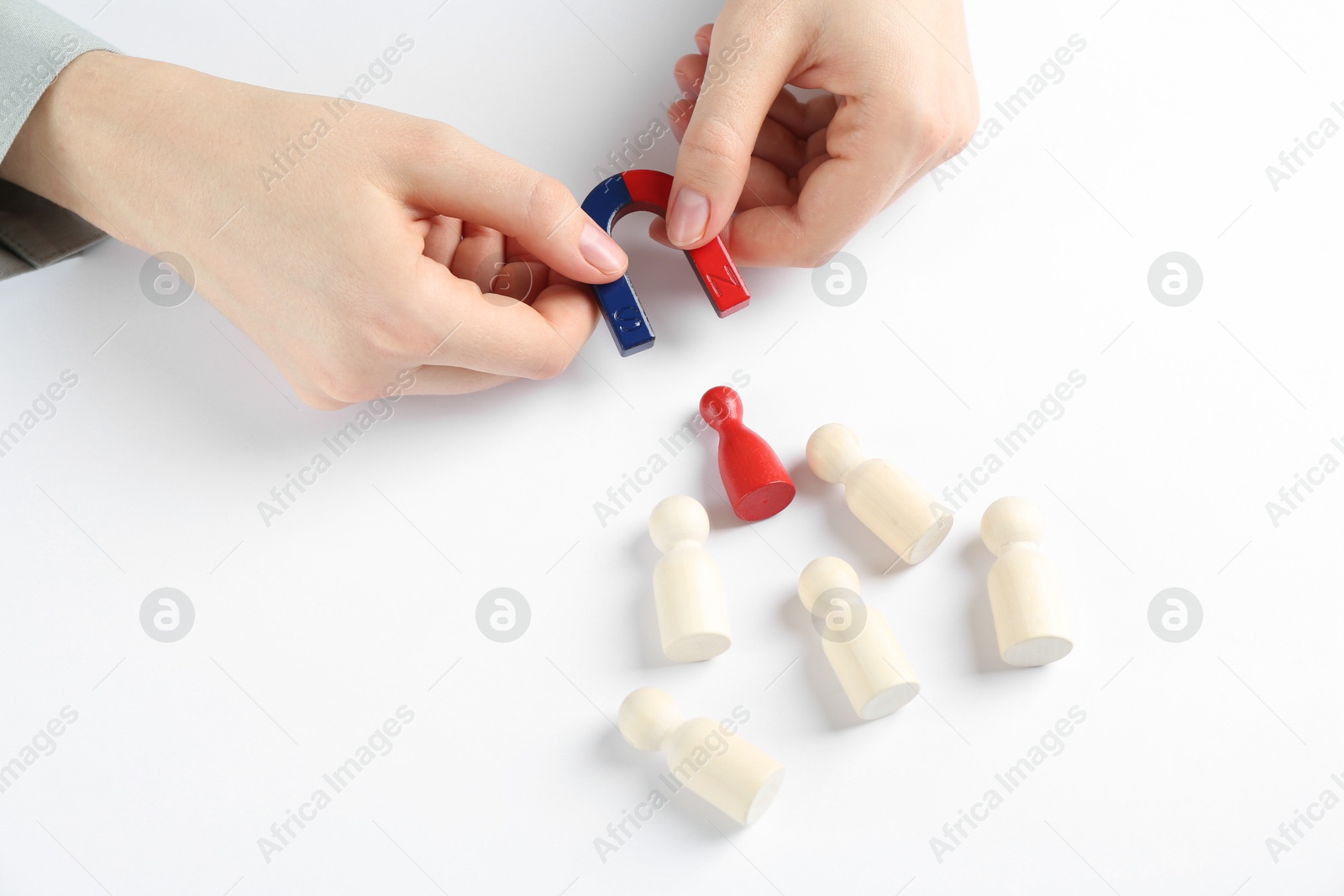 Photo of Woman with magnet attracting game pieces at white table, closeup