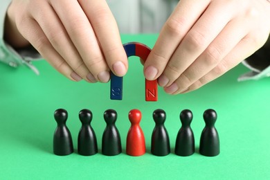 Photo of Woman with magnet attracting game pieces at green table, closeup