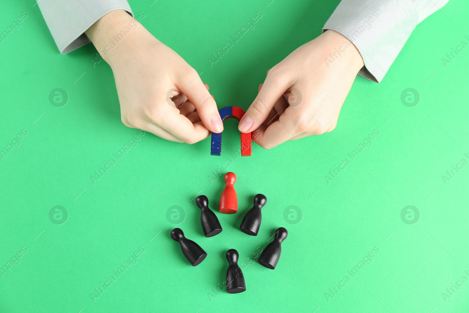 Photo of Woman with magnet attracting game pieces at green table, above view