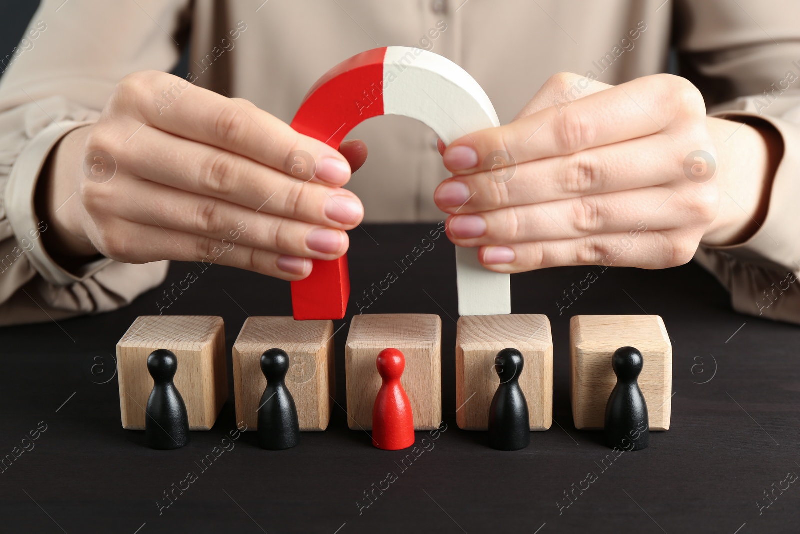 Photo of Woman with magnet attracting game pieces at wooden table, closeup