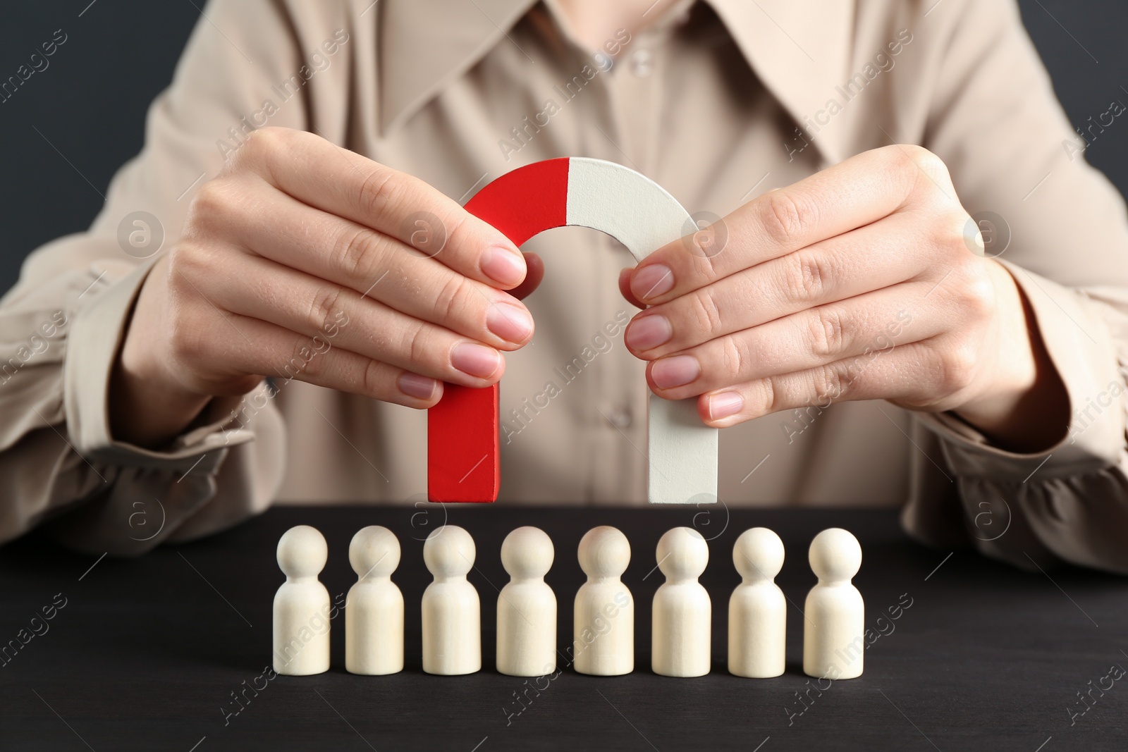 Photo of Woman with magnet attracting game pieces at wooden table, closeup