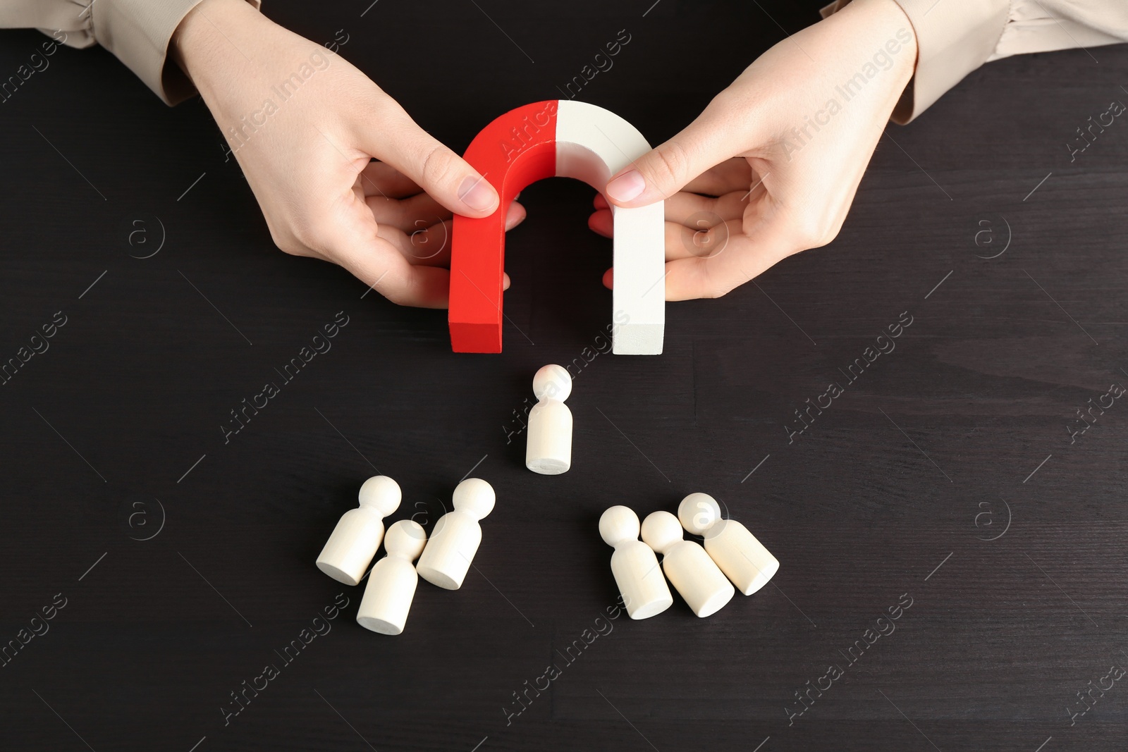 Photo of Woman with magnet attracting game pieces at wooden table, above view