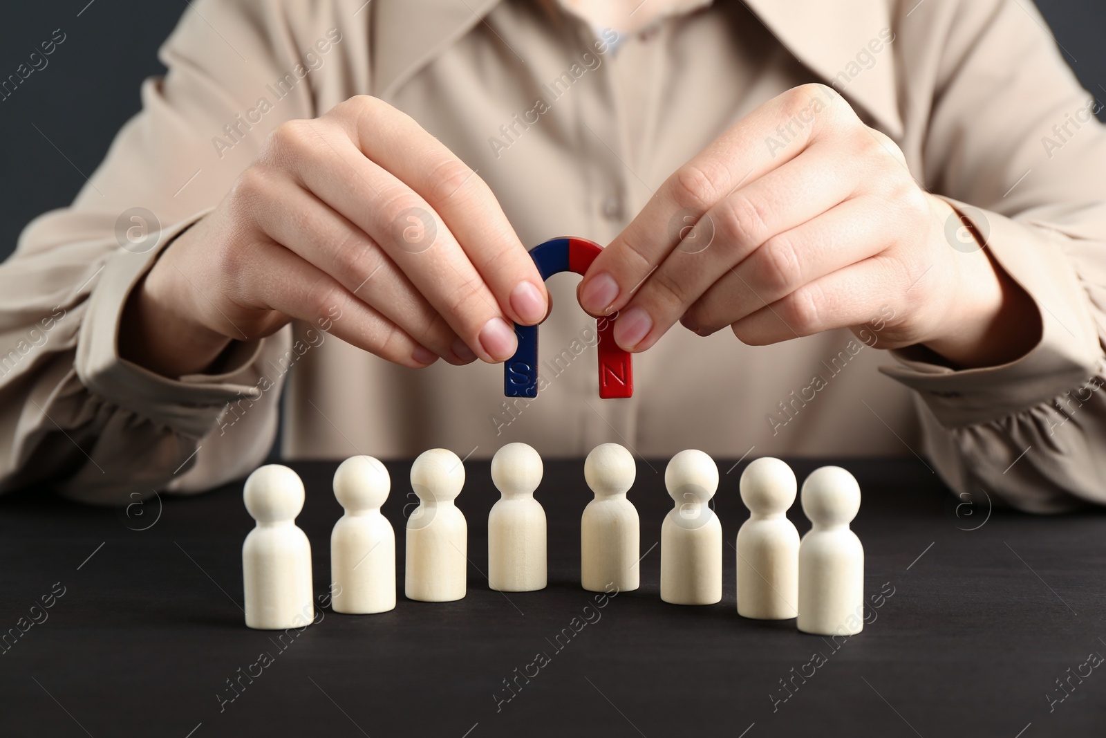 Photo of Woman with magnet attracting game pieces at wooden table, closeup