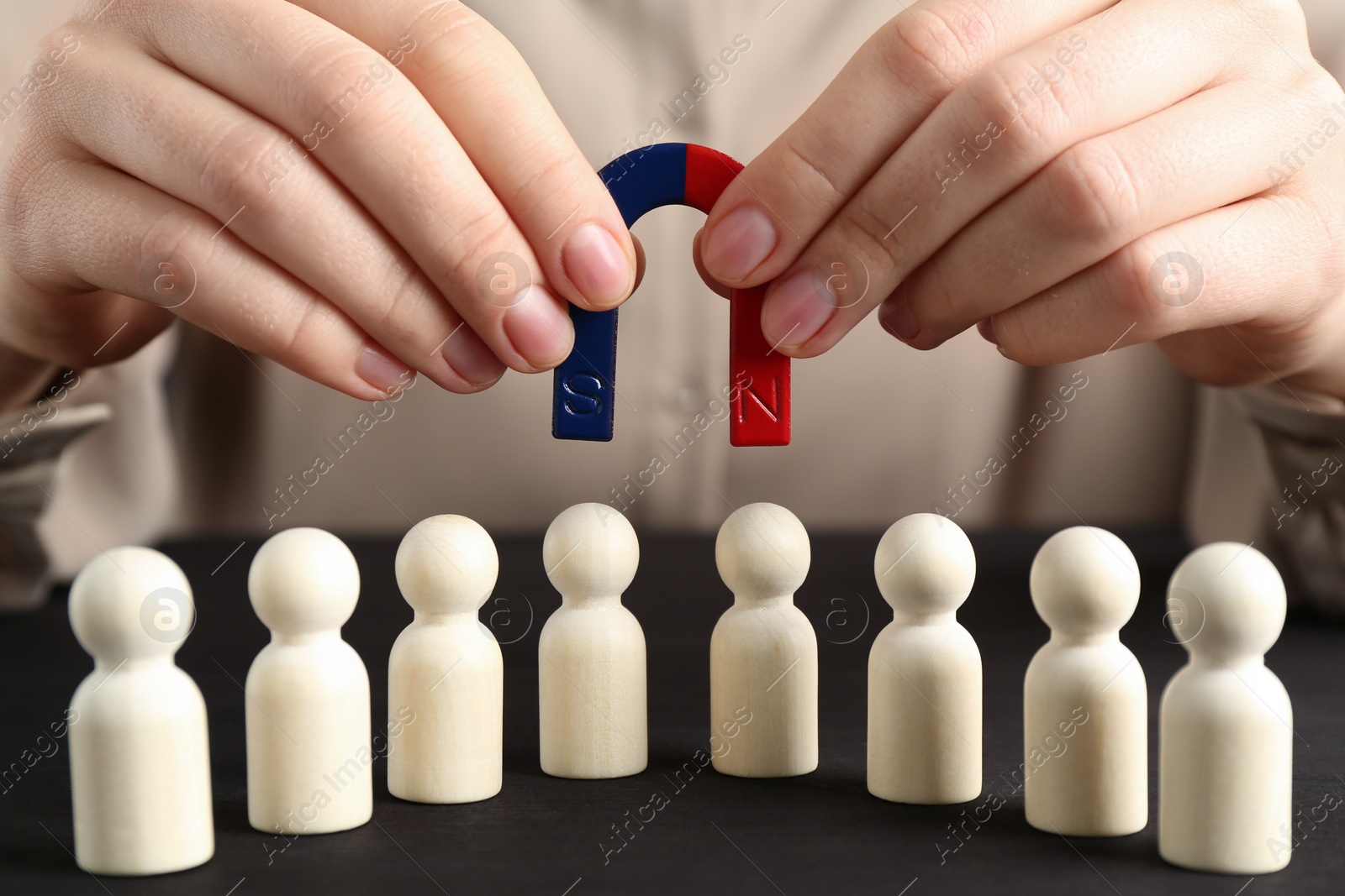 Photo of Woman with magnet attracting game pieces at wooden table, closeup