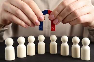 Photo of Woman with magnet attracting game pieces at wooden table, closeup