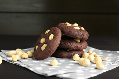 Photo of Delicious chocolate cookies with hazelnuts on black wooden table, closeup