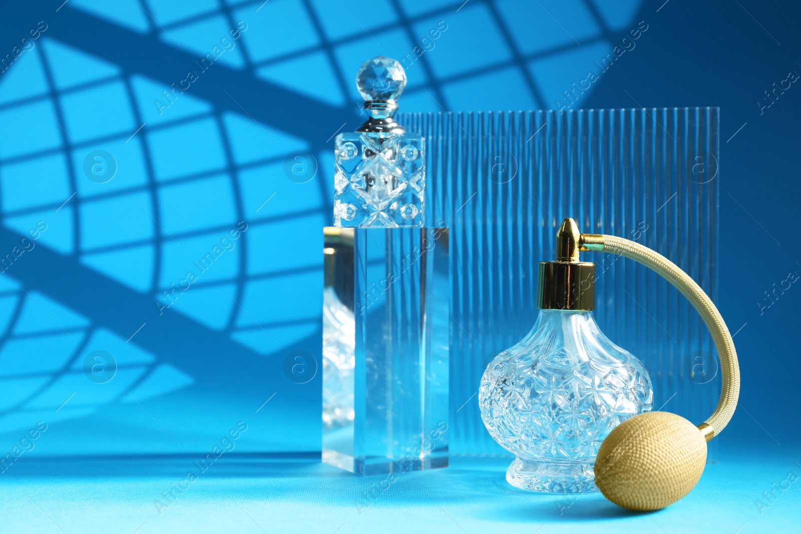 Photo of Stylish presentation of perfume bottles on light blue background, space for text