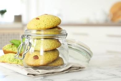 Photo of Delicious mint chocolate chip cookies in jar on white marble table, closeup. Space for text