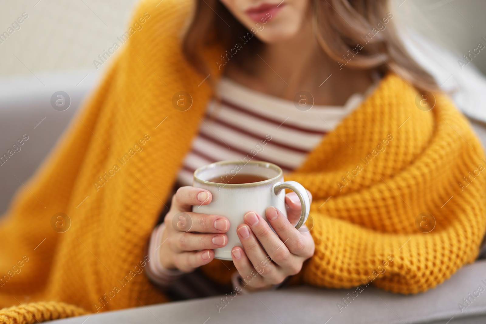 Photo of Charming young woman with cup of hot drink on sofa at home, closeup. Autumn atmosphere