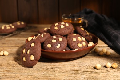 Photo of Tasty chocolate cookies with hazelnuts on wooden table, closeup