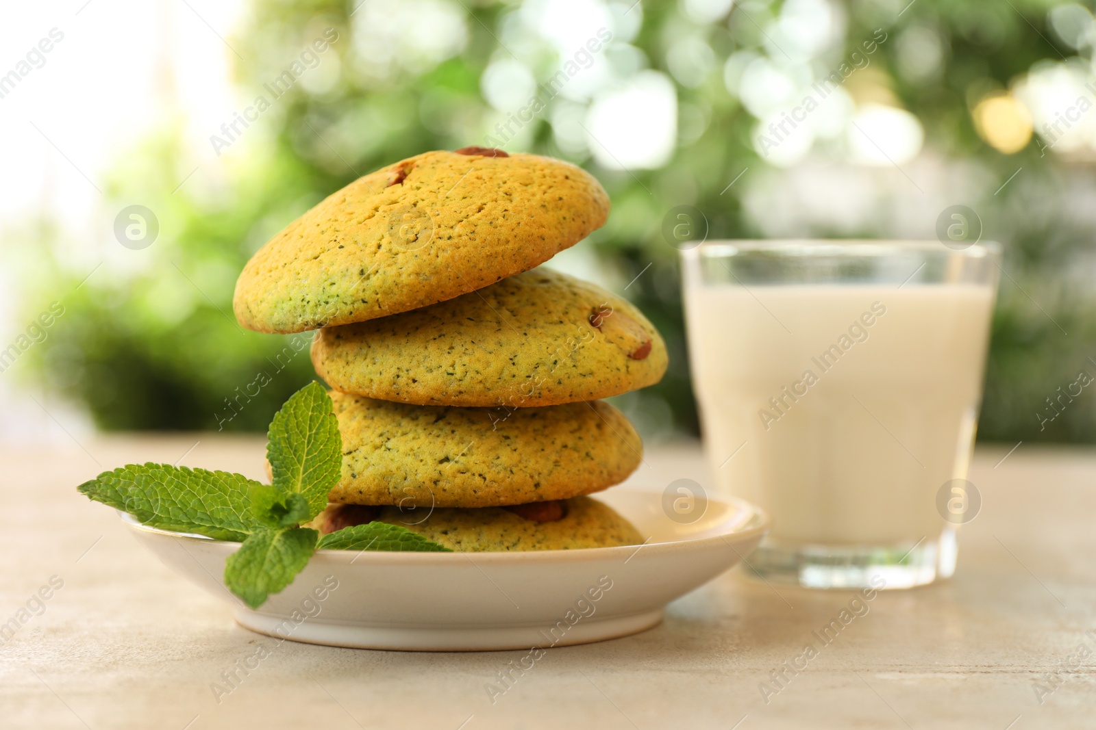 Photo of Delicious mint chocolate chip cookies and milk on light table, closeup