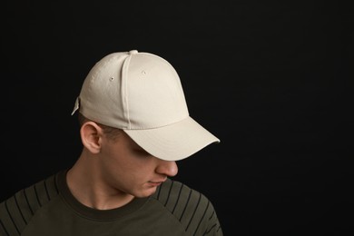 Photo of Man in stylish baseball cap on black background. Mockup for design