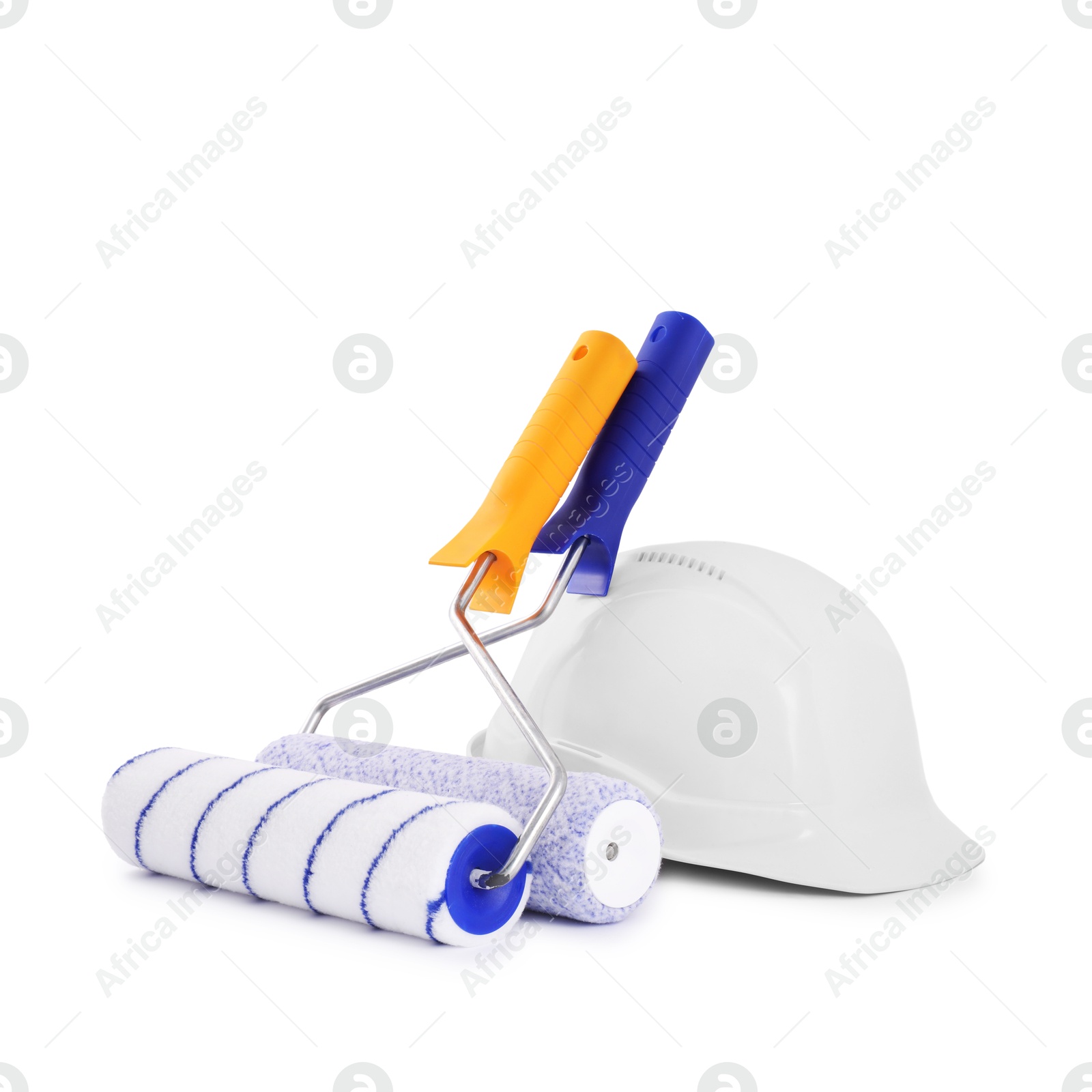 Photo of Paint roller brushes and hardhat isolated on white. Construction tool and safety equipment