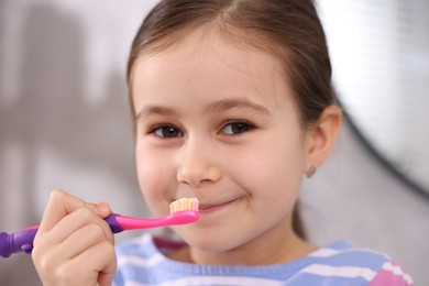 Photo of Cute girl with toothbrush in bathroom, closeup