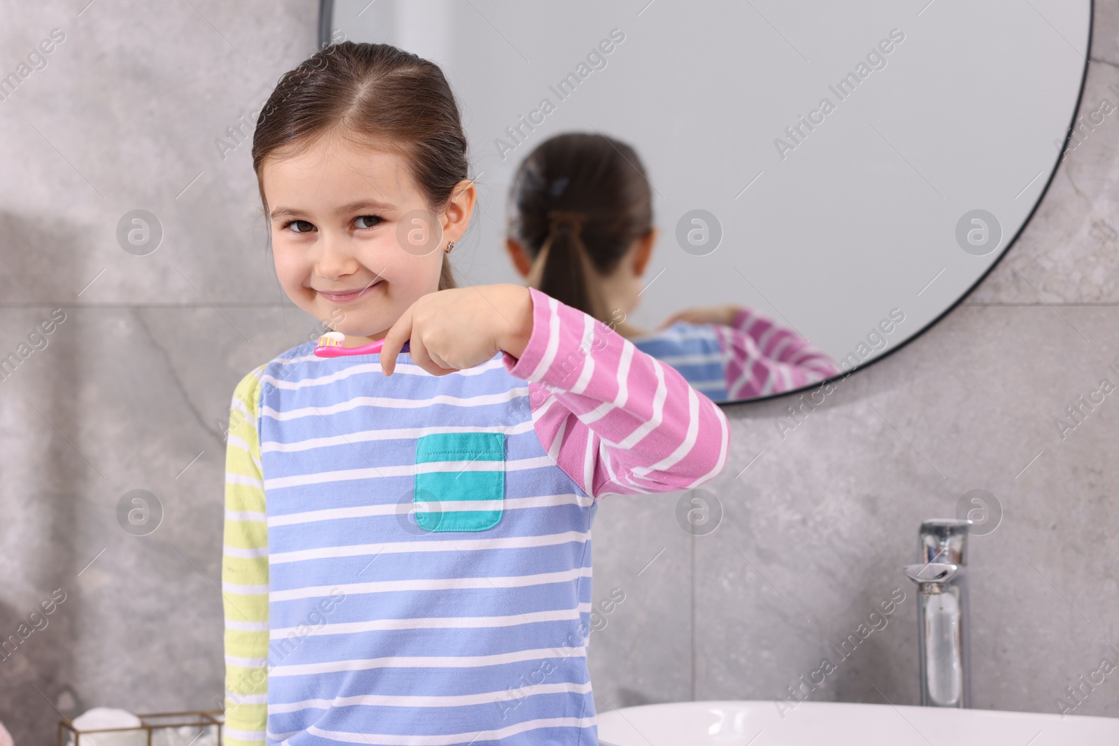 Photo of Cute girl with toothbrush in bathroom. Personal hygiene