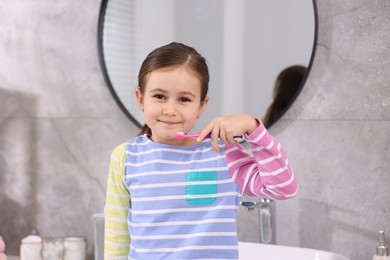 Photo of Cute girl with toothbrush in bathroom. Personal hygiene