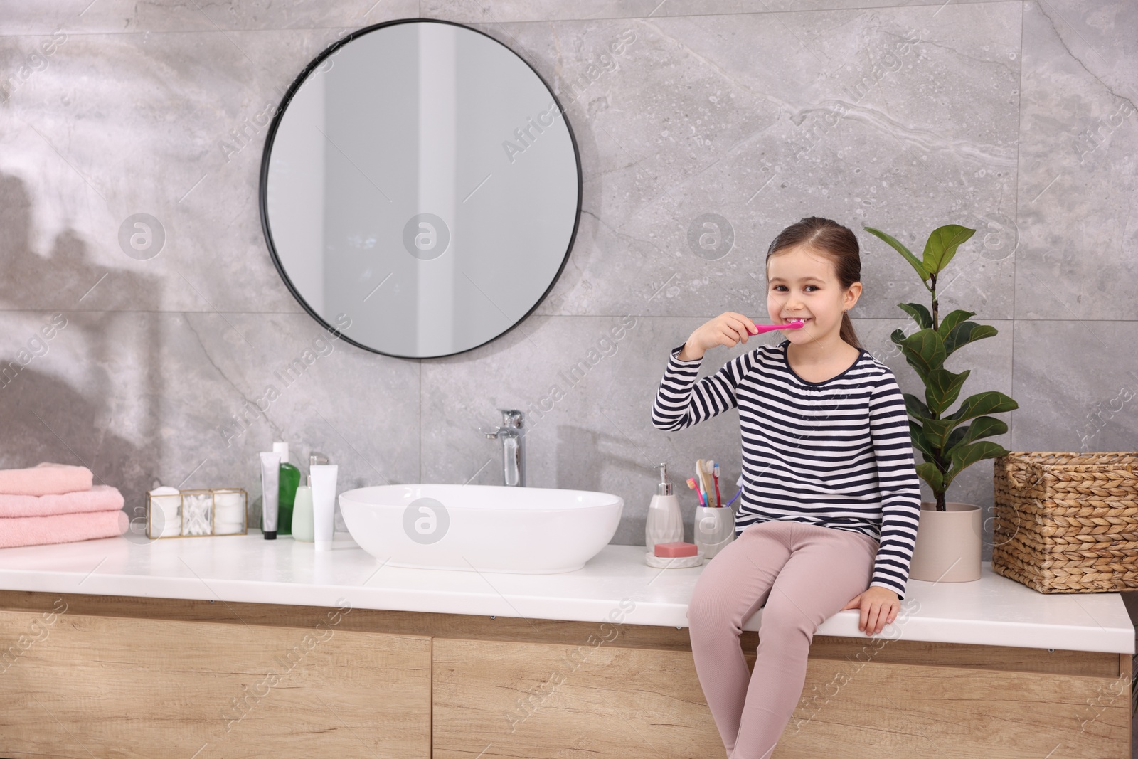 Photo of Cute girl brushing her teeth in bathroom