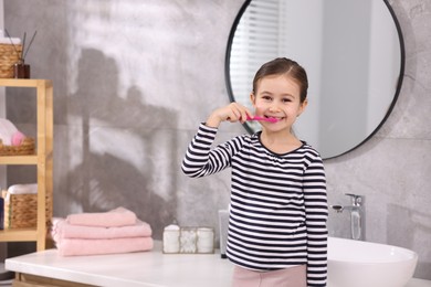 Photo of Cute girl brushing her teeth in bathroom