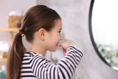 Photo of Cute girl brushing her teeth in bathroom