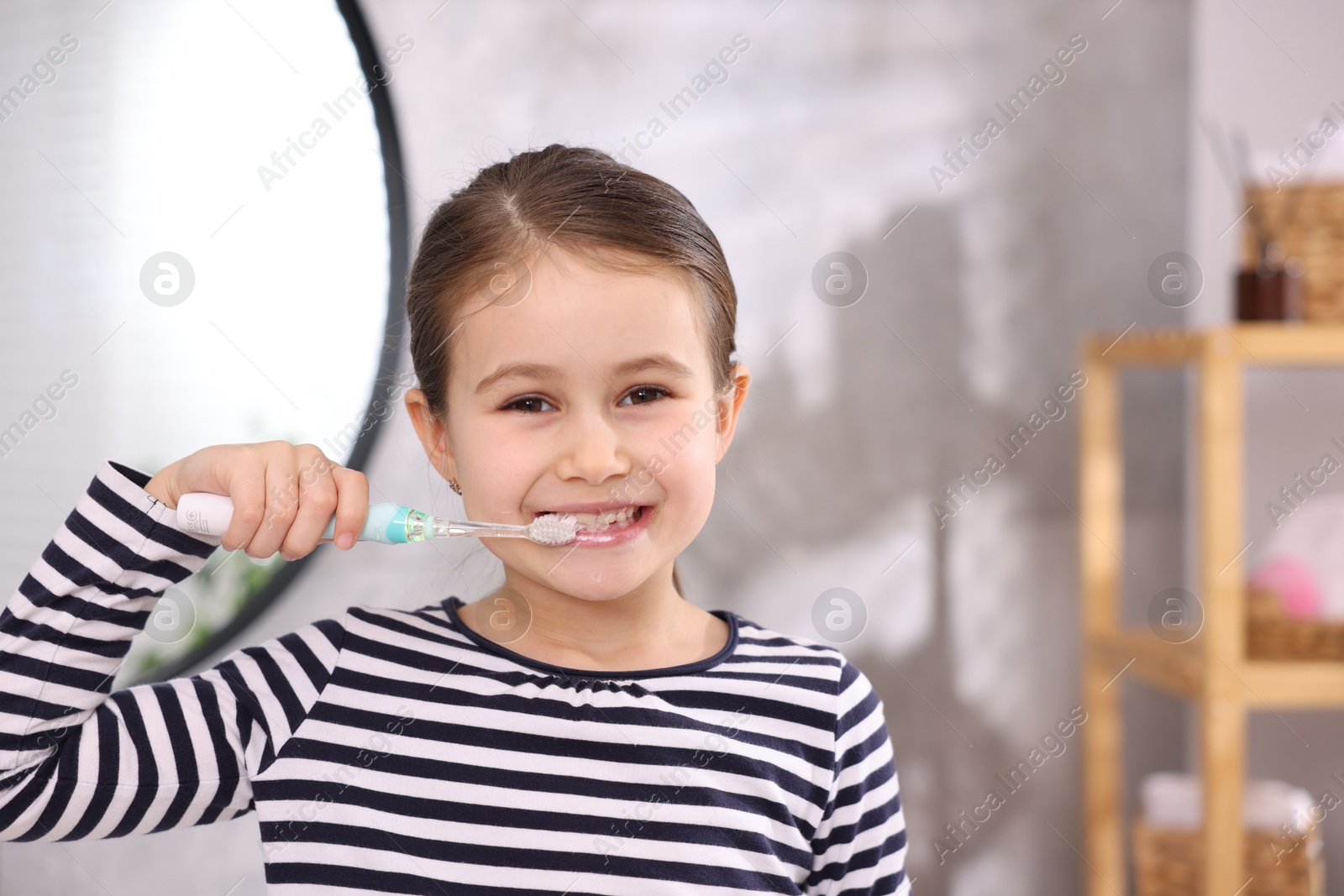 Photo of Cute girl brushing her teeth in bathroom