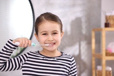 Photo of Cute girl brushing her teeth in bathroom