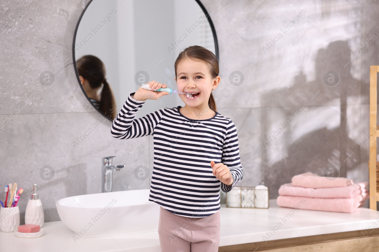 Photo of Cute girl brushing her teeth in bathroom