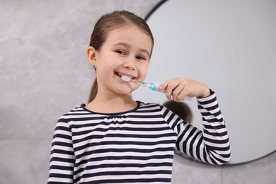 Photo of Cute girl brushing her teeth in bathroom