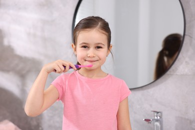 Photo of Cute girl brushing her teeth in bathroom