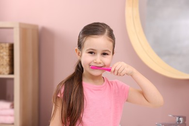 Photo of Cute girl brushing her teeth in bathroom