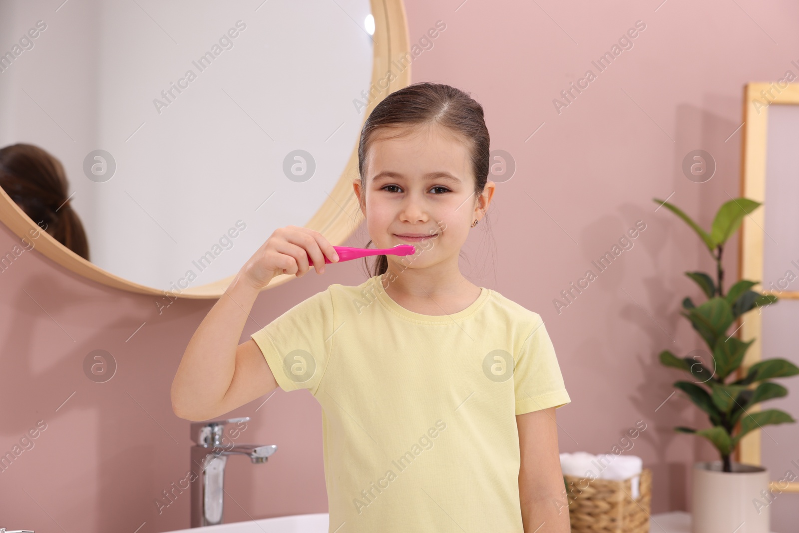 Photo of Cute girl brushing her teeth in bathroom